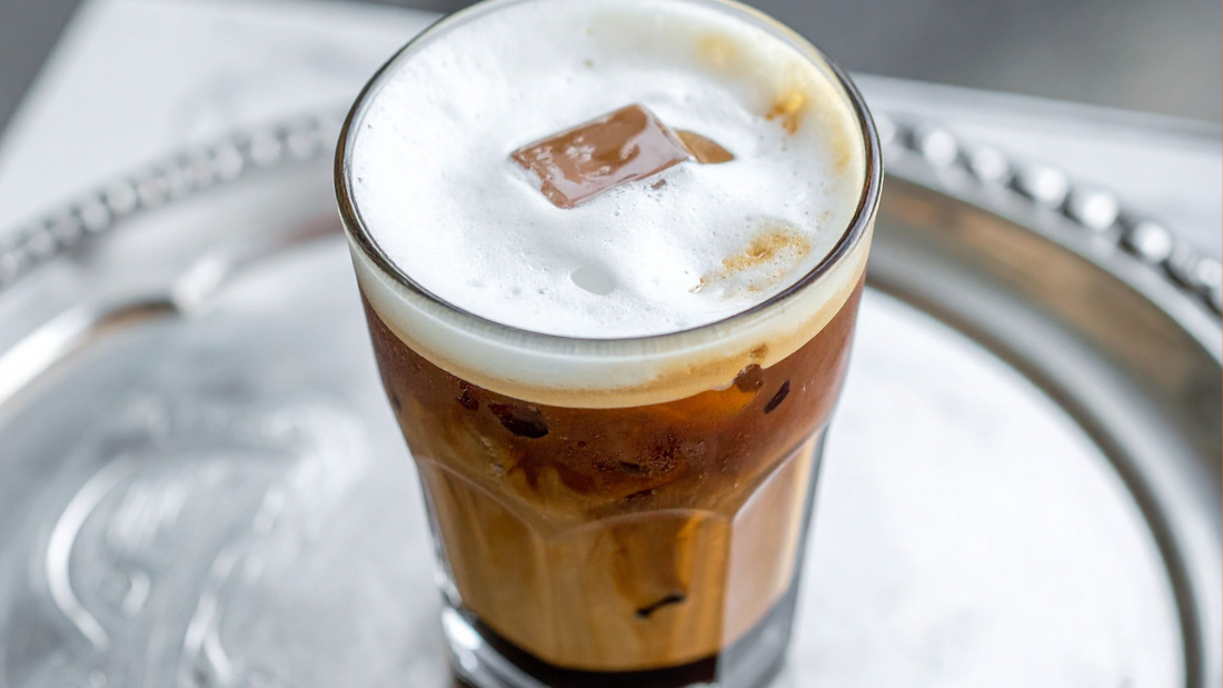 glass of nitro cold brew poured over ice with a creamy cascading foam head