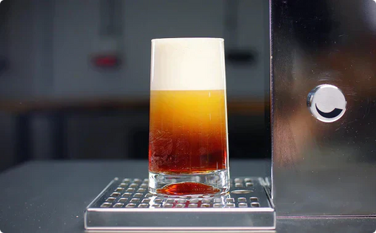 nitro cold brew dispensed from hardtank, showing a thick cascading foam head in a clear glass