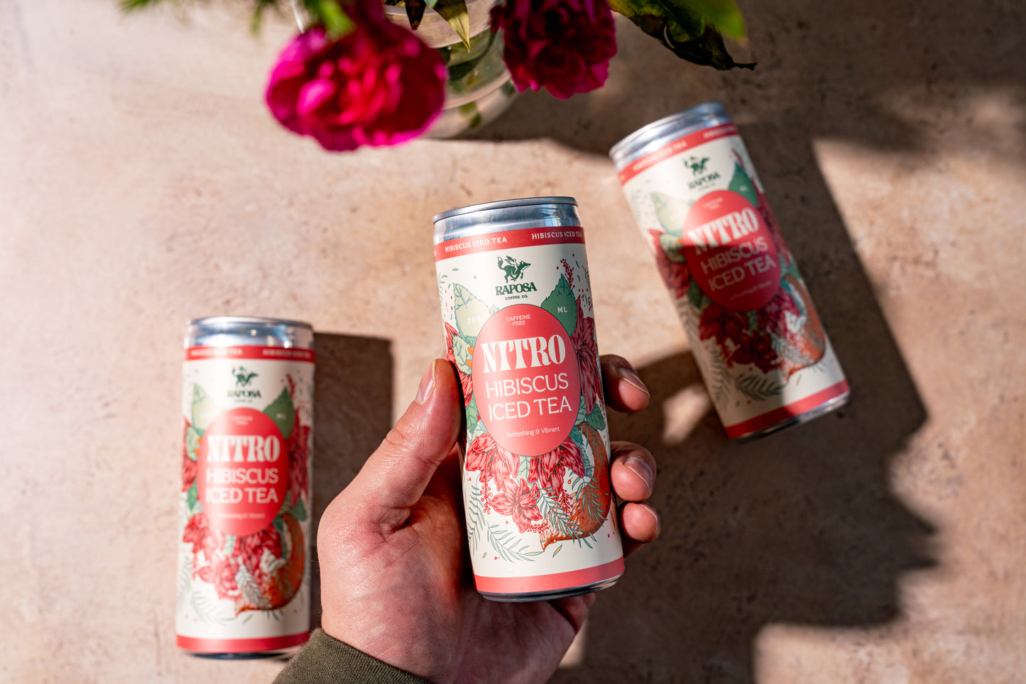 Raposa Nitro Hibiscus Iced tea cans held in hand
