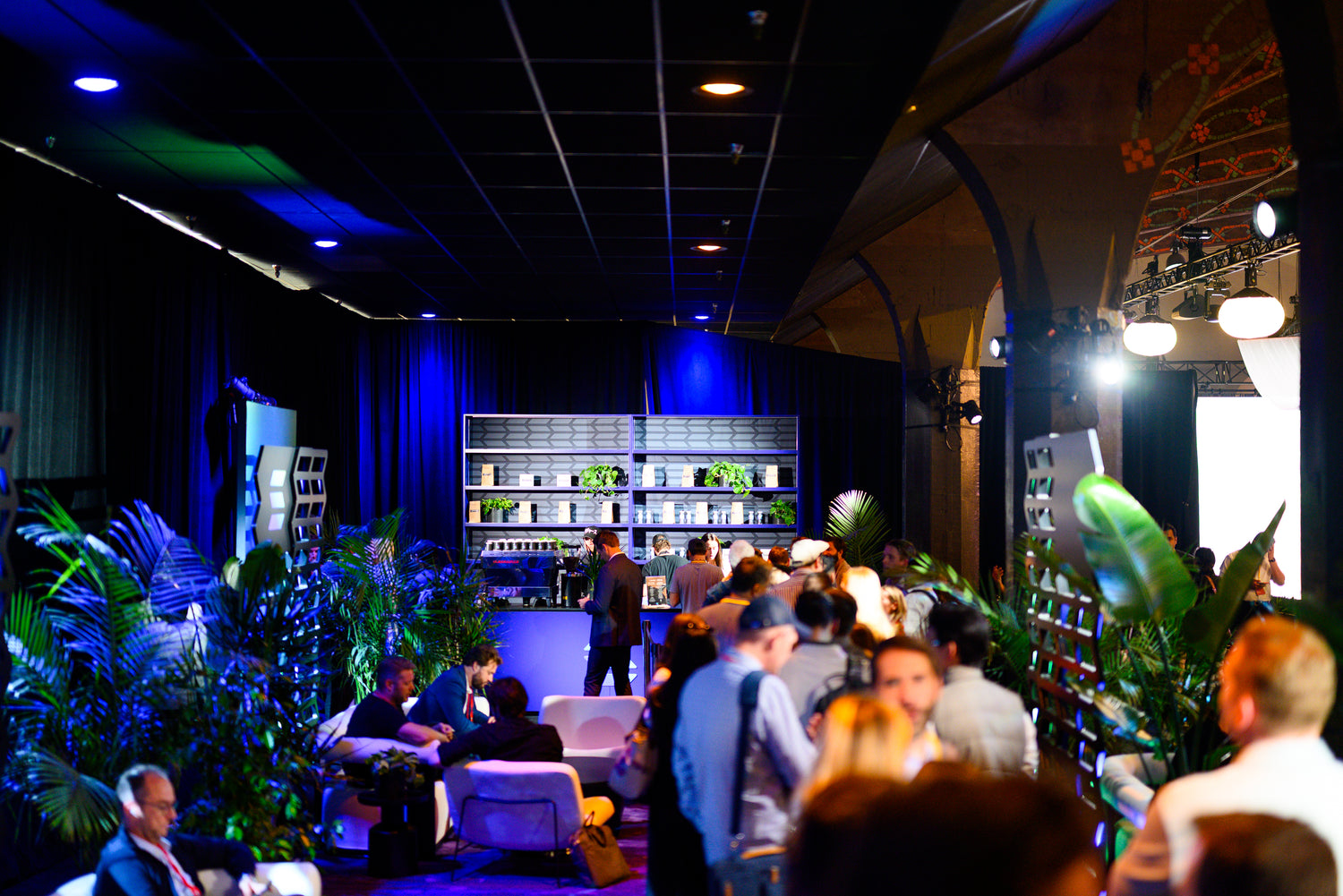 Event or conference setting with people and plants in a modern indoor space.