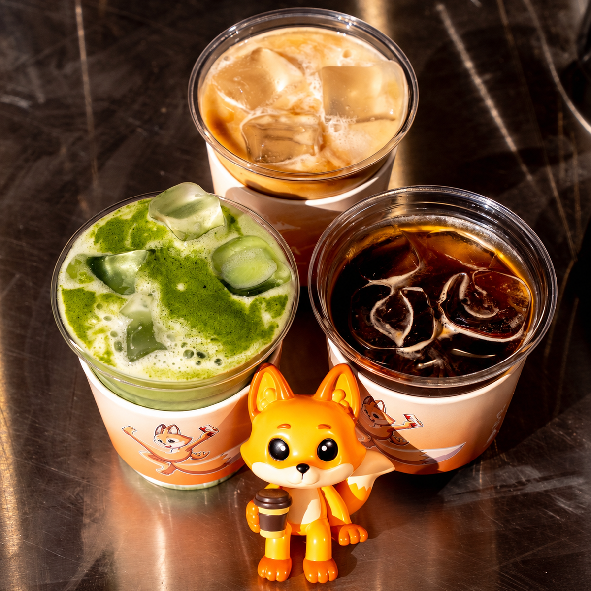 three iced raposa drinks with an orange fox figurine