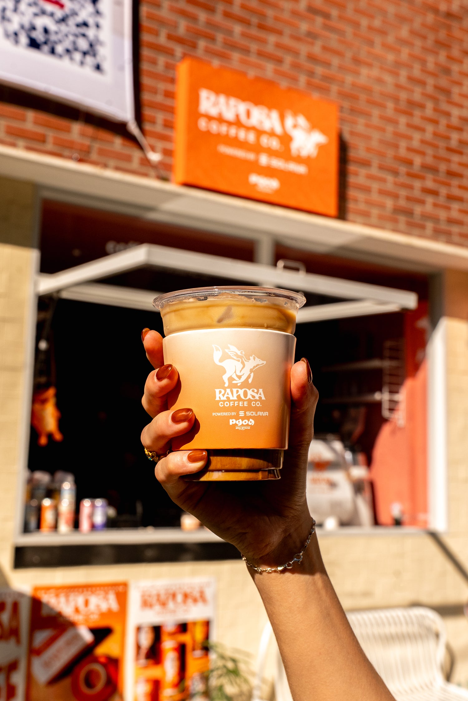 person holding a raposa iced coffee drink in front of raposa cafe