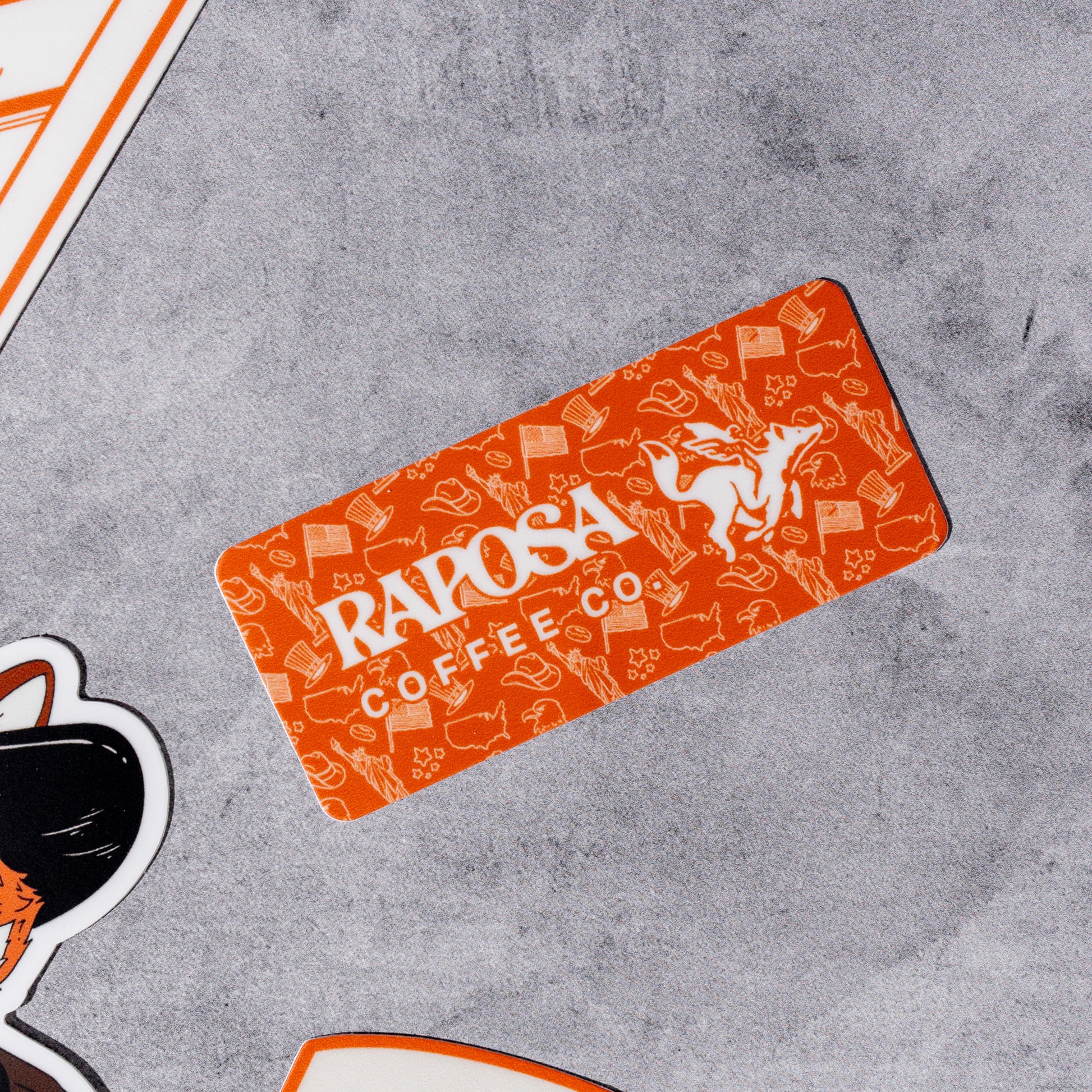 Orange 'Raposa Coffee Co' vinyl sticker with brand logo on a gray surface
