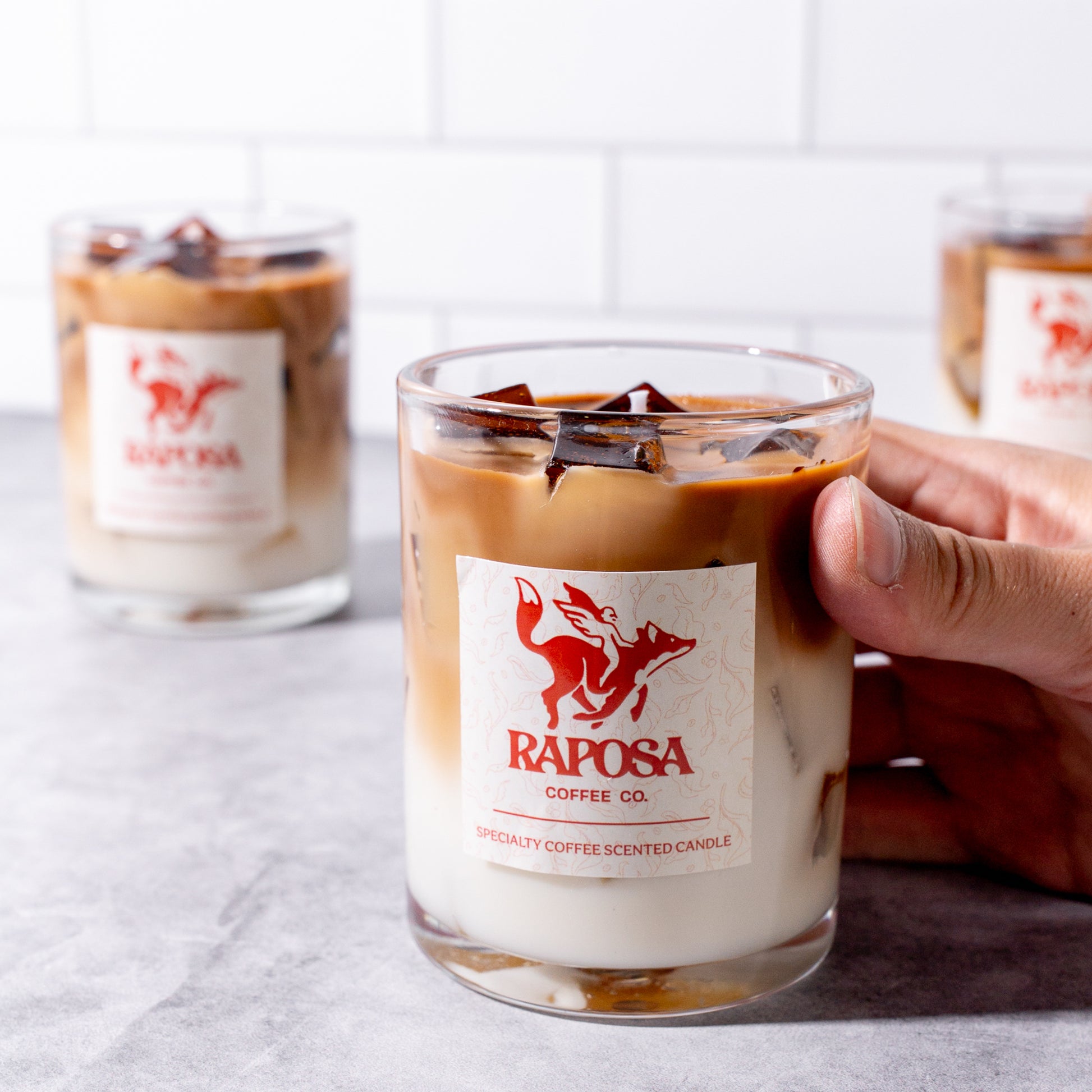 raposa coffee-scented candle in glass jar held in hand