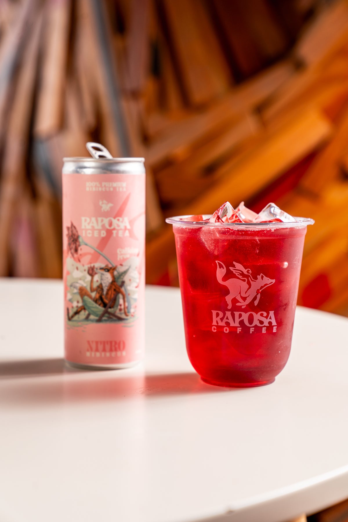 raposa hibiscus iced tea in a cup next to the can