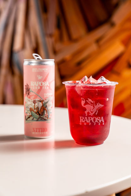 raposa hibiscus iced tea in a cup next to the can