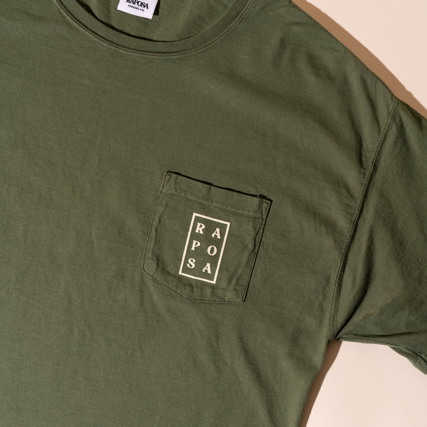 Raposa pocket tee olive close-up of front pocket logo print
