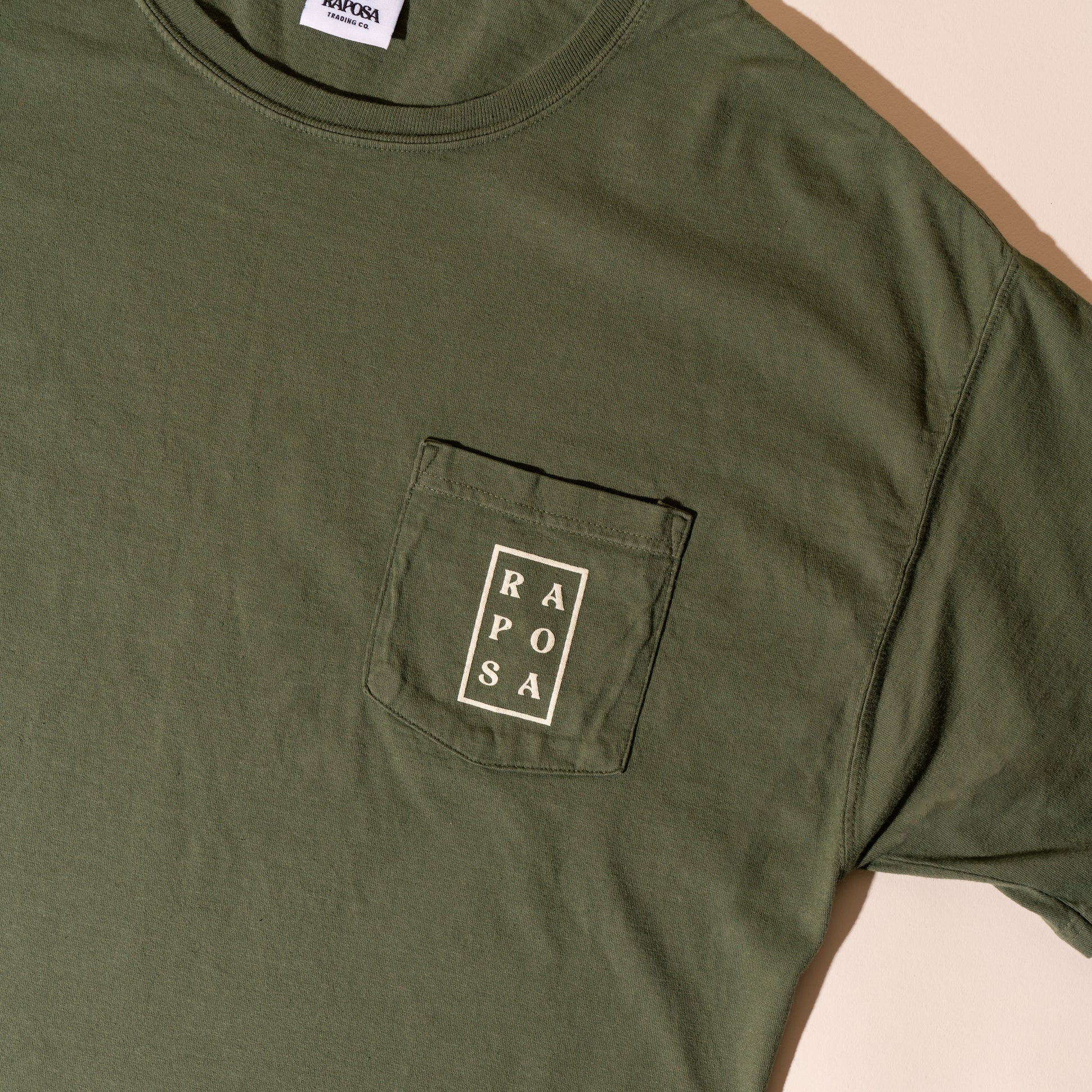 Raposa pocket tee olive close-up of front pocket logo print
