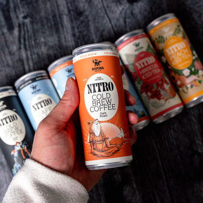 Hand holding Raposa nitro cold brew cans from the starter pack variety